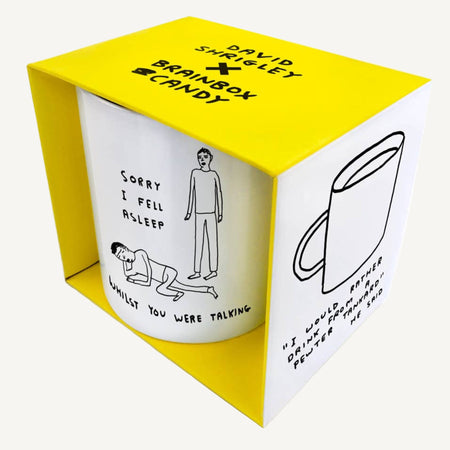 White mug with black text and illustrations in a yellow box, featuring the artist David Shrigley.