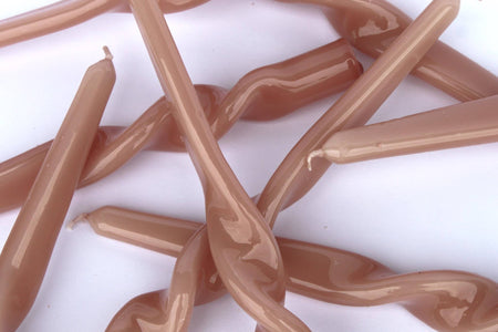 Close-up of a jumble of Maegen plaster pink twisted candles on a white background