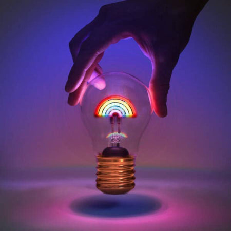 Rechargeable rainbow light is glowing in six different colours and held by a person's hand.
