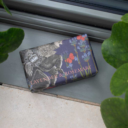 Bar of soap with archival Kew illustrations and surrounded by green leaves.