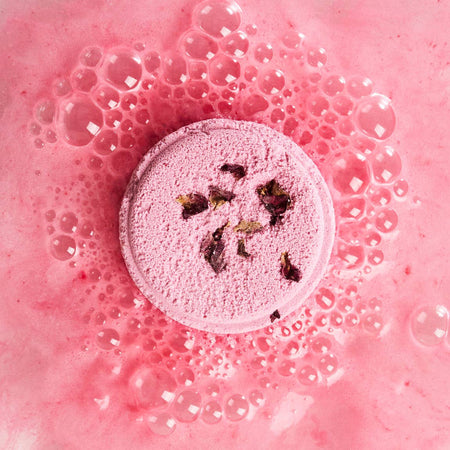 Pink shower steamer with rose petals on a pink bubble bath background