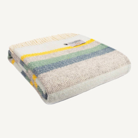 Striped woollen illusion throw with yellow, blue, grey and green pattern on a white background