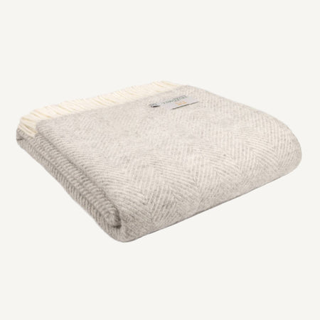 Folded neutral toned hazel throw in fishbone pattern on a white background