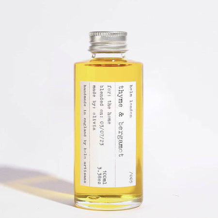 Glass bottle with aluminium screw top lid of thyme & bergamot diffuser oil with a label on a white background