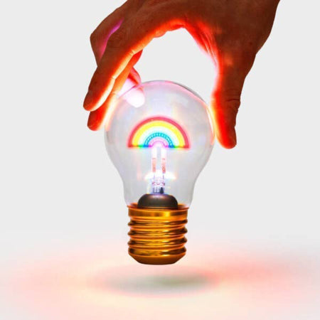 Rechargeable rainbow light is glowing in six different colours and held by a person's hand.
