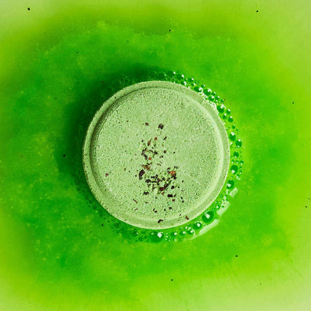 A green peppermint and herb shower steamer bubbling on a green background