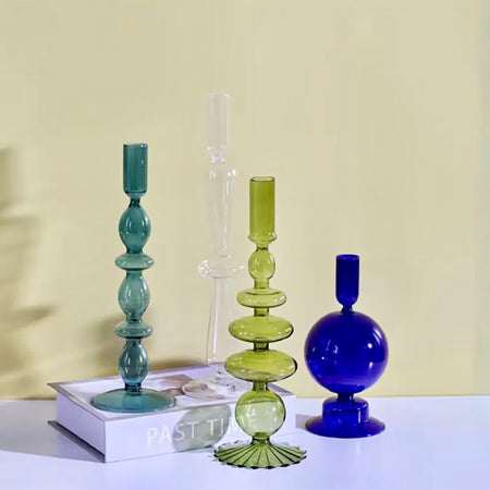 Three colorful glass vases on a white surface with a yellow background