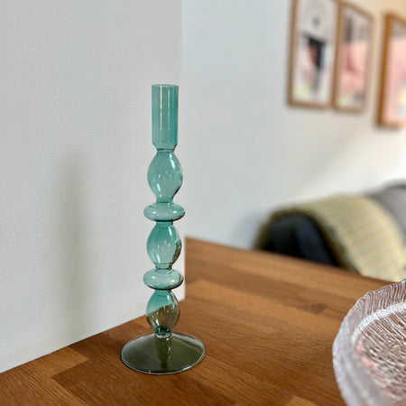 Blue glass candlestick on a wooden table with a blurred background