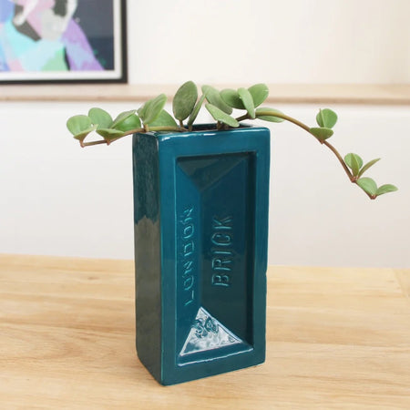 Teal brick-shaped vase with 'London Brick' branding on a wooden surface