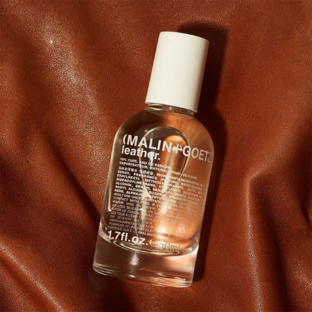 Malin+Goetz leather conditioner bottle on a brown leather background