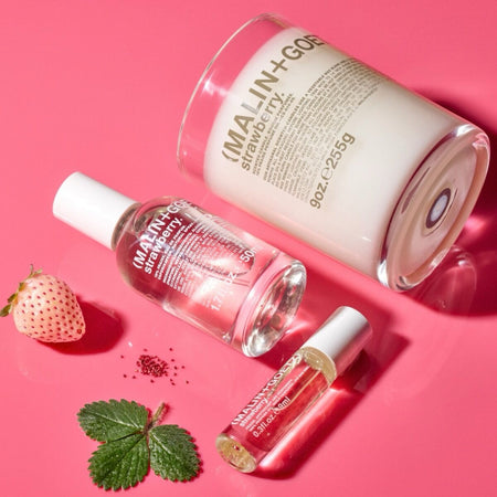 Malin+Goetz strawberry eau de parfum. Three skincare products with visible branding on a pink background