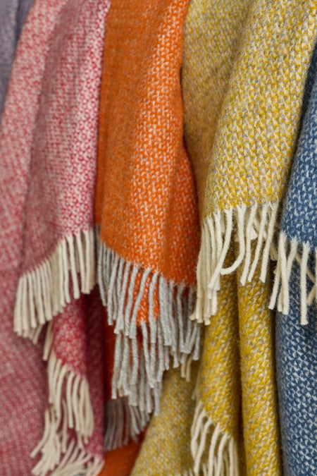 Close-up of colourful woven blankets in mixed colours in illusion pattern with cream fringes.