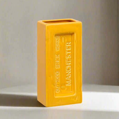 Yellow brick-shaped vase with 'Outwood Brick Works Manchester' text on a neutral background