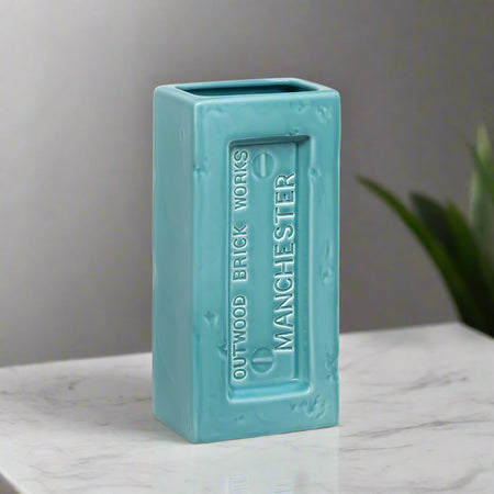 Turquoise rectangular vase with 'Outwood Brick Works Manchester' branding on a white background. Perfect for design lovers who appreciate function with an industrial edge.