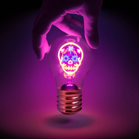 Rechargeable colourful skull light is glowing in various colours and held by a person's hand.