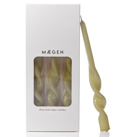 Twisted leaf green taper candle with 'Máegen' branded packaging and see through window on a white background