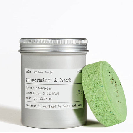 Aluminium screw top container of peppermint & herb shower steamers with a green steamer on a white background