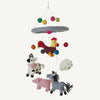 Children's mobile with farm animal toys hanging from colorful strings on a white background