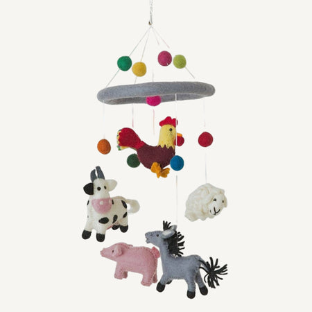 Children's mobile with farm animal toys hanging from colorful strings on a white background