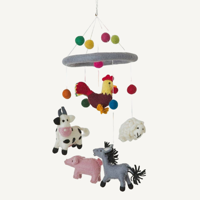 Children's mobile with farm animal toys hanging from colorful strings on a white background