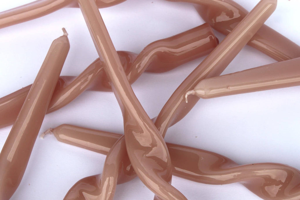 Close-up of a jumble of Maegen plaster pink twisted candles on a white background