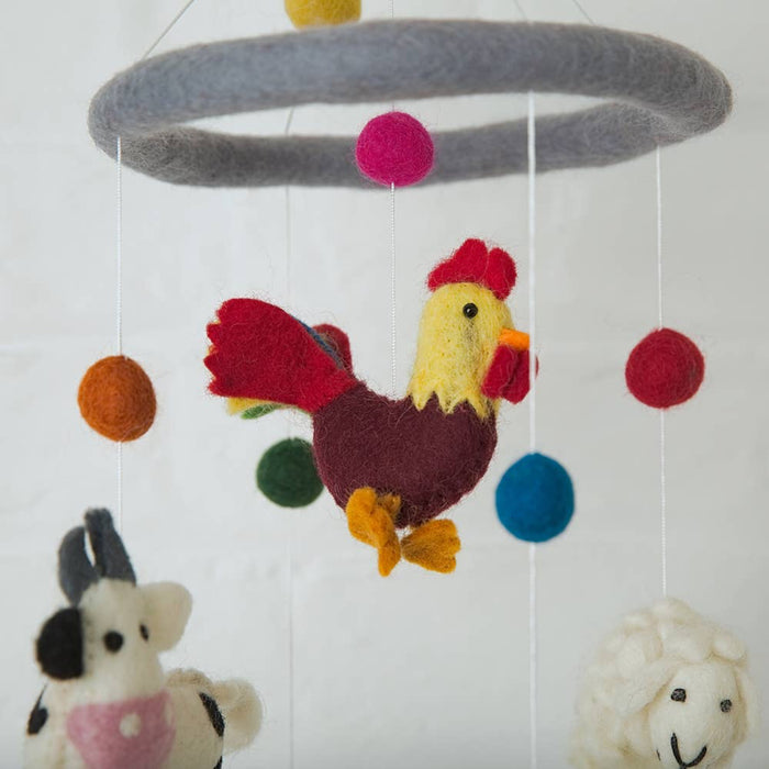 Felted animal mobile with rooster, cow, sheep and felt balls on a white background