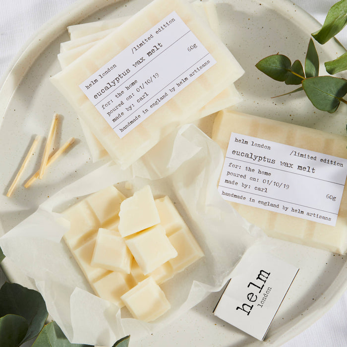 Helm London eucalyptus wax melts on a white plate with labels and greenery.