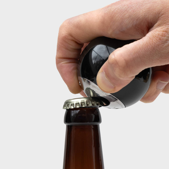Man opening a bottle of beer using the bottle opener made from an actual 8 ball.