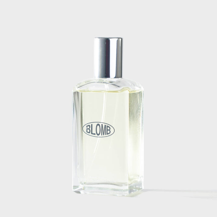 Clear perfume bottle with silver cap on a white background, featuring the brand 'Blomb'.