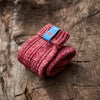 Folded red knitted Icelandic Saga socks with an Iceland flag brand label on a wooden log background. Lambswool and cotton rich to get you through the cold Arctic nights.