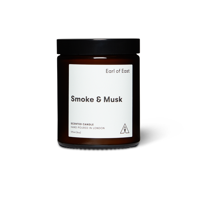 Amber glass candle jar with screw top labeled 'Smoke & Musk' by 'Earl of East', hand poured in London