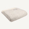 Folded neutral toned hazel throw in fishbone pattern on a white background