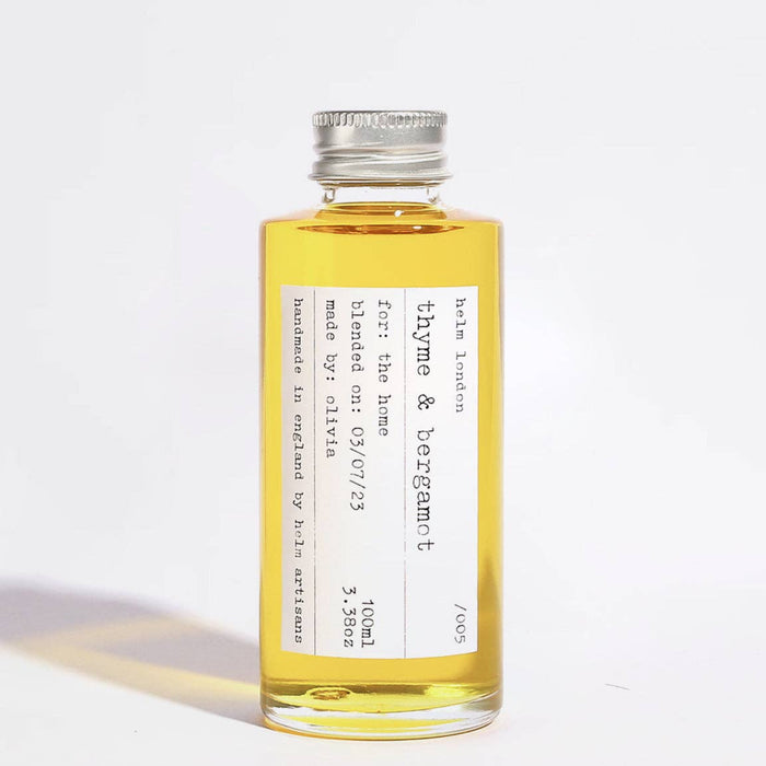 Glass bottle with aluminium screw top lid of thyme & bergamot diffuser oil with a label on a white background