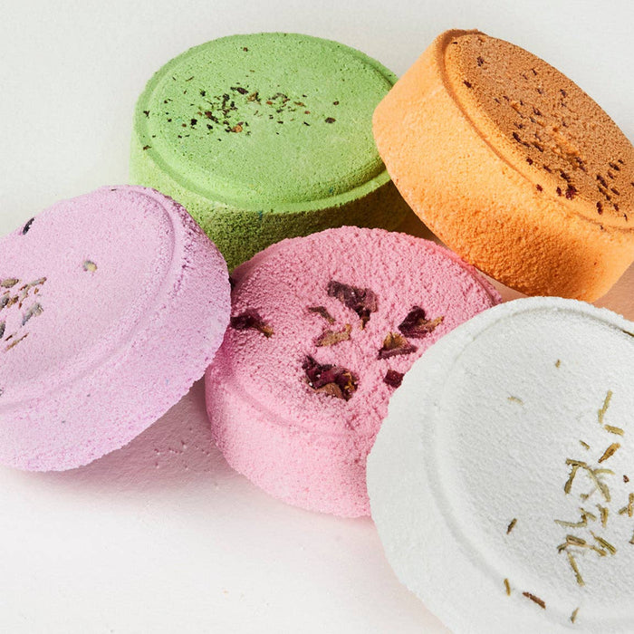 A mix of colourful shower steamers with visible textures and toppings on a white background