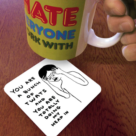 Mug with colorful text and a coaster with a graphic and text on a wooden surface
