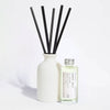 Elegant, white ceramic and reusable diffuser with black reeds and a glass bottle with aluminium screw top lid on a light background.