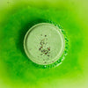 A green peppermint and herb shower steamer bubbling on a green background