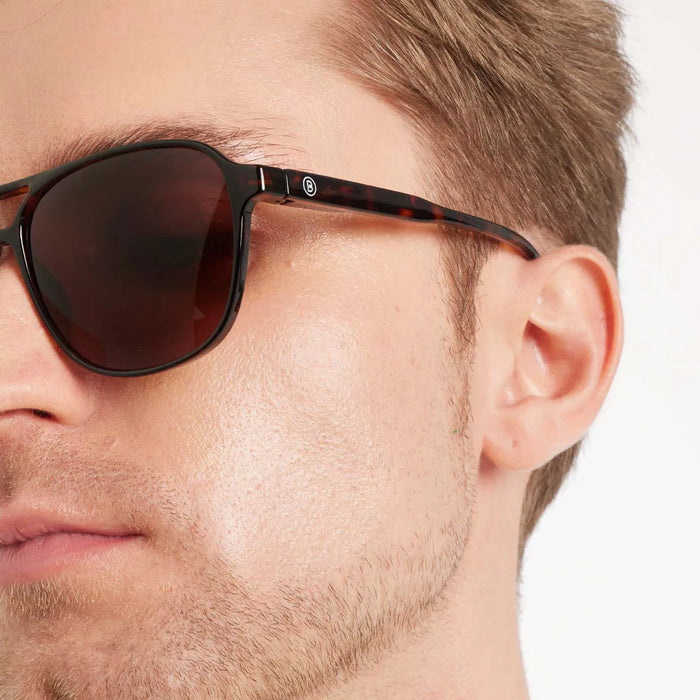 Close-up of a person wearing sunglasses with a neutral background