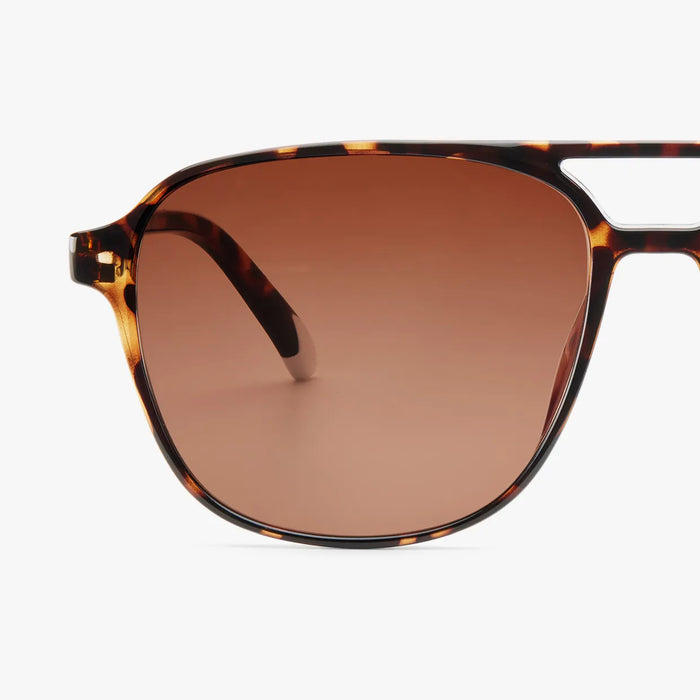 Sunglasses with tortoiseshell frame and brown lenses on a white background