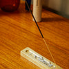 Earl of East Smoke and Musk incense stick burning on a wooden surface with a blurred background