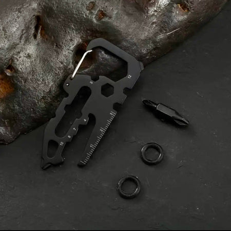 Black multi-tool with components on a dark surface with a rock background