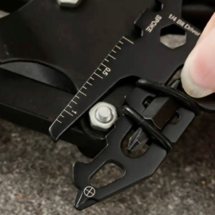 Black multi-tool with various tools and a ruler on a dark background