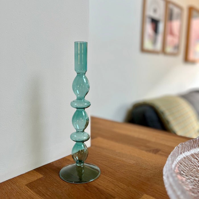 Blue glass candlestick on a wooden table with a blurred background