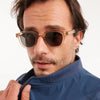 Man wearing sunglasses and a blue jacket on a white background