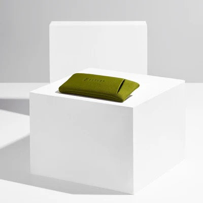 Green folded glasses case on a white pedestal against a gray background