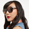Woman wearing oversized sunglasses with a neutral background