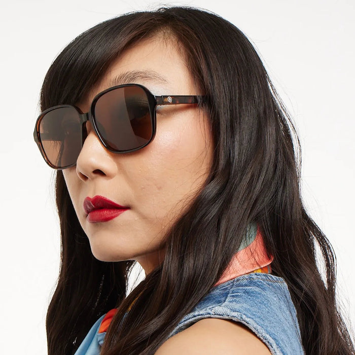 Woman wearing oversized sunglasses with a neutral background