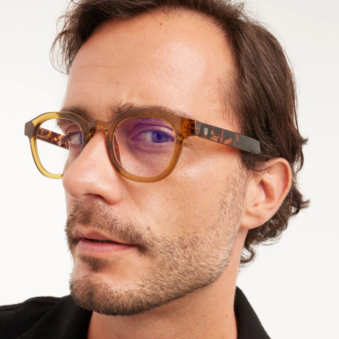 Close-up of a person wearing tortoiseshell glasses with a neutral background