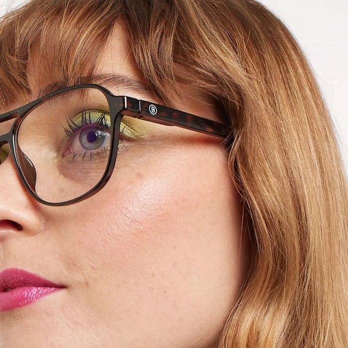 Close-up of a person wearing glasses with a neutral background
