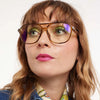 Close-up of a person wearing glasses with a neutral background
